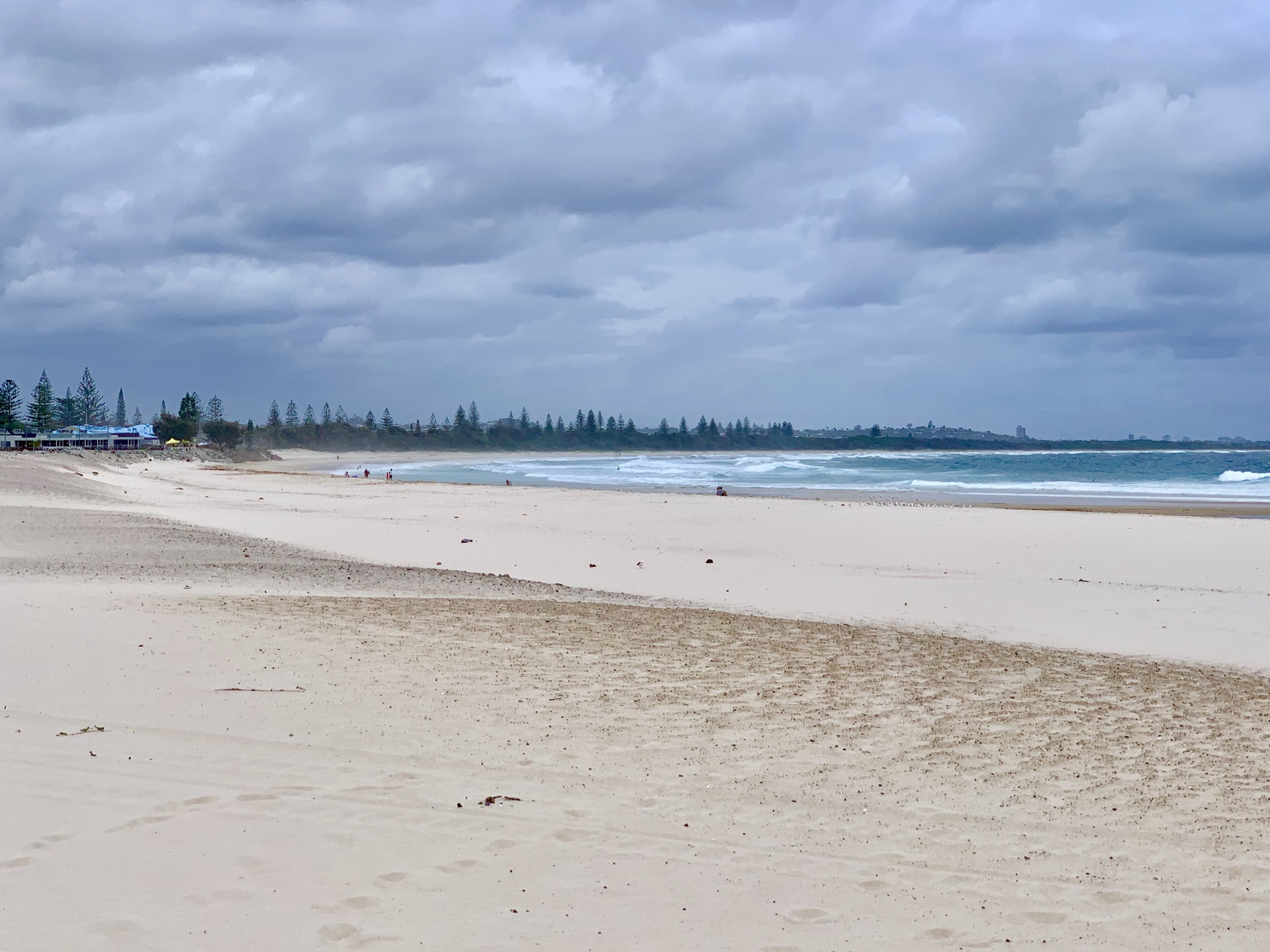 A long open sweep of Kingscliff Beach beneath a clouded sky